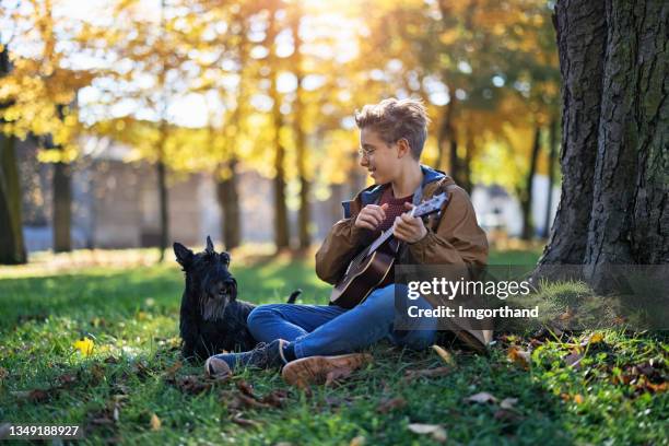 kleiner junge und sein hund spielen im öffentlichen park - young boy enjoying music stock-fotos und bilder