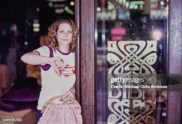 Woman wearing a Led Zeppelin 1973 American Tour t-shirt, on the front of which the name of the promoter 'Concerts West, ' giving a thumbs down...