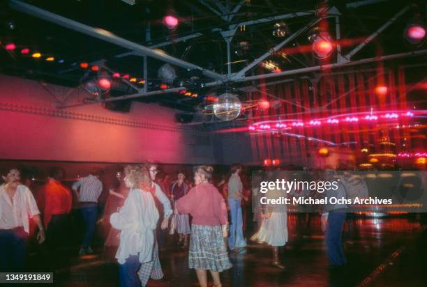 Dancers on the dancefloor of an nightclub, a glitter ball hanging from the ceiling, circa 1975.