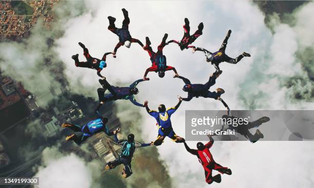 group of skydivers holding hands - complicité photos et images de collection