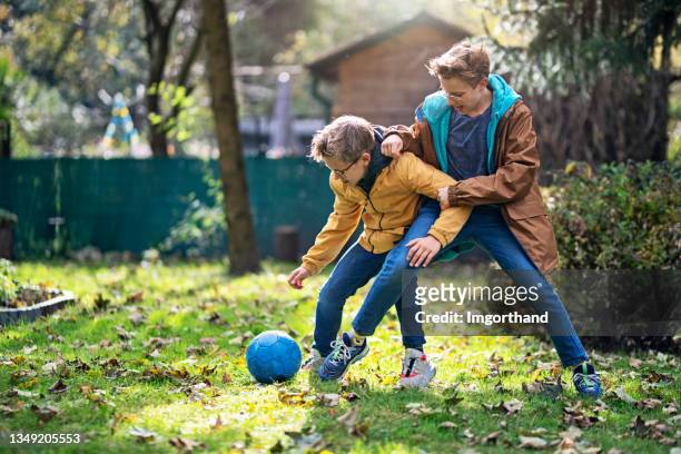 teenage boys having fun playing soccer in the backyard - football grass stock pictures, royalty-free photos & images