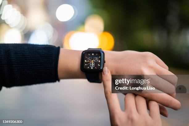 a pair of hands with watches on the street at night - wristwatch stock pictures, royalty-free photos & images