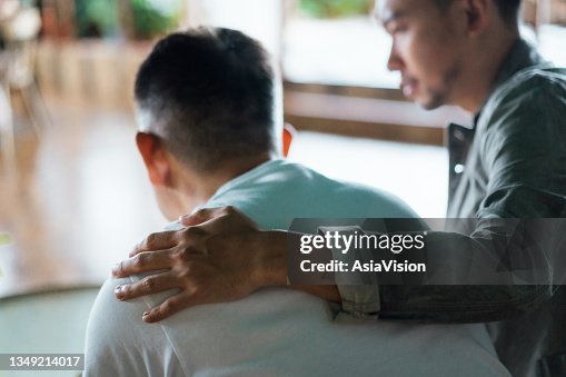 Vista trasera del hijo y el padre anciano sentados juntos en casa. Hijo cuidando a su padre, poniéndole la mano en el hombro, consolándolo y consolándolo. Amor familiar, vinculación, cuidado y confianza Vista trasera del hijo y el padre anciano sentados juntos en casa. Hijo cuidando a su padre, poniéndole la mano en el hombro, consolándolo y consolándolo. Amor familiar, vinculación, cuidado y confianza