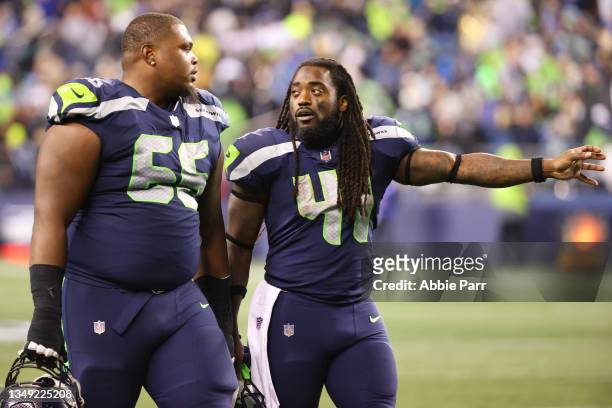 Gabe Jackson and Alex Collins of the Seattle Seahawks have a conversation while heading in for halftime against the New Orleans Saints at Lumen Field...