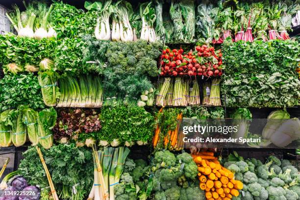 fresh greens and vegetables on a display in a supermarket - supermarket ストックフォトと画像