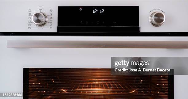 buttons and control panel of a modern oven with the clock timer flashing. - oven stockfoto's en -beelden