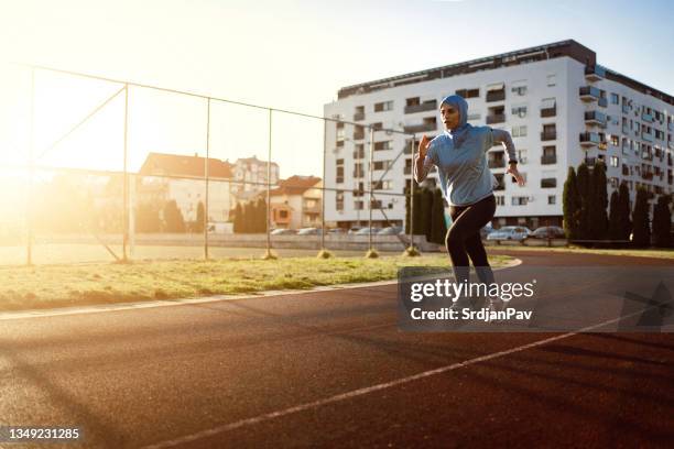 modest muslim sportswoman, running on the sports track, during sunset - religious headwear stock pictures, royalty-free photos & images