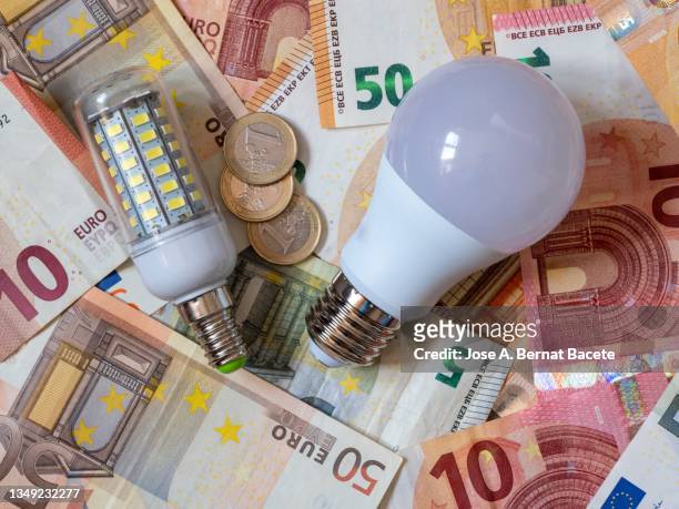 low consumption led light bulb and euro banknotes and coins - electricity bill stock pictures, royalty-free photos & images