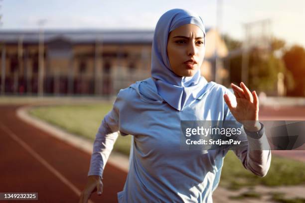 muslim woman in modest sports clothing and hijab running on the sports track - women with hijab stock pictures, royalty-free photos & images