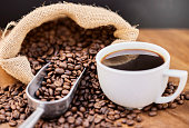 Shot of coffee beans and a cup of black coffee on a wooden table