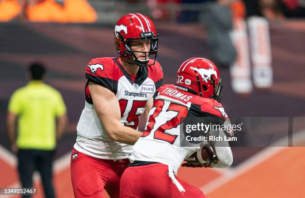 Quarterback Michael O'Connor of the Calgary Stampeders hands the ball off to Roc Thomas during CFL football action at BC Place against the BC Lions...