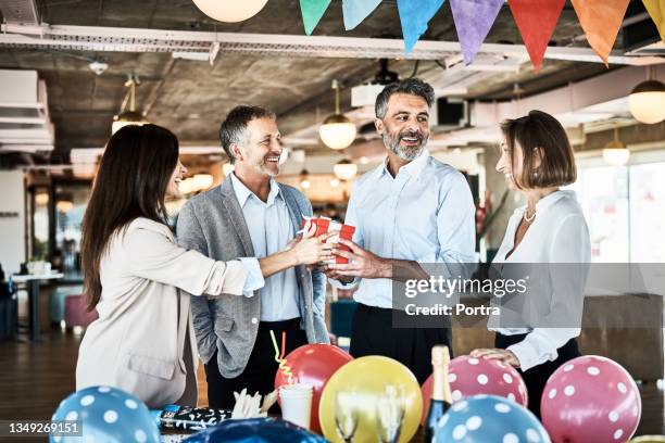 les gens d’affaires offrent un cadeau d’anniversaire à un collègue au bureau - cadeau danniversaire photos et images de collection