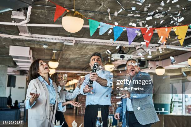 geschäftsleute feiern geburtstag mit party popper im büro - birthday party stock-fotos und bilder