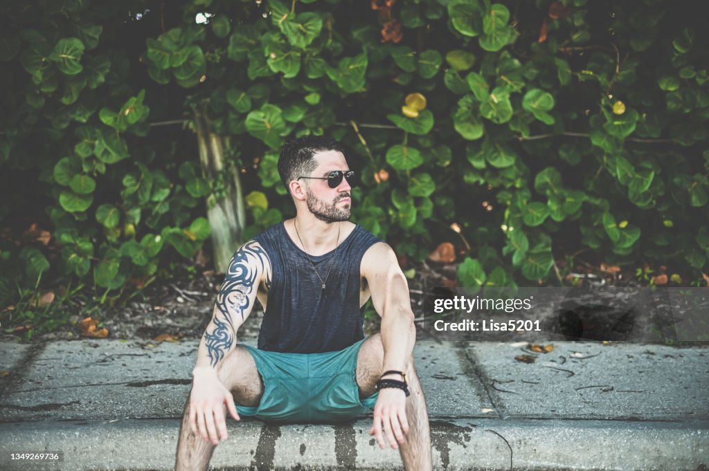 Beau gars tatoué en lunettes de soleil d’aviateur avec une attitude cool en portrait candide
