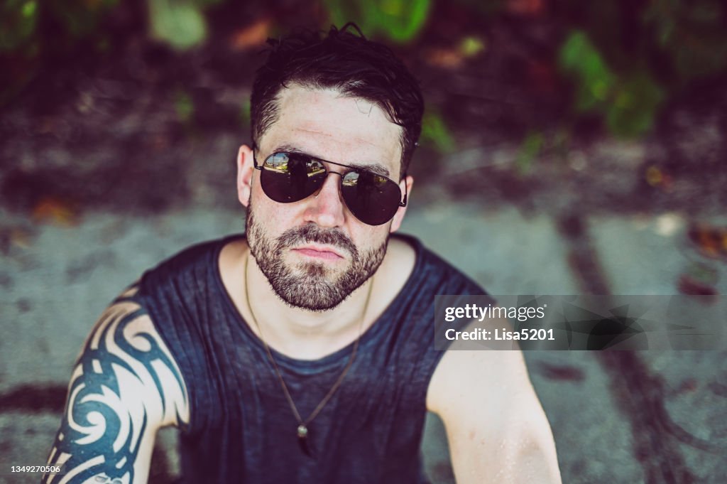 Beau gars tatoué en lunettes de soleil d’aviateur avec une attitude cool en portrait candide