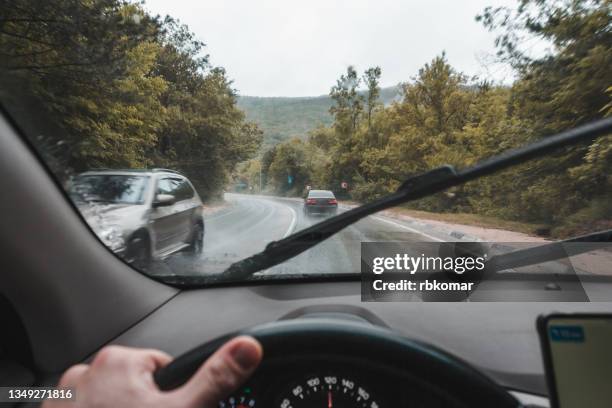 driver driving a car on a dangerous mountain curve - ruitenwisser stockfoto's en -beelden