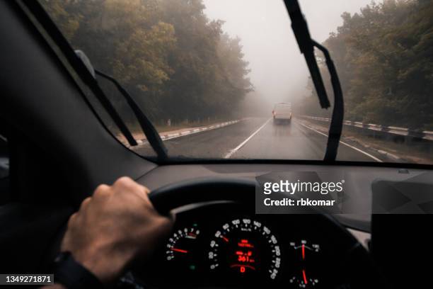 driving in the rain on highway in misty forest - point of view driving stock-fotos und bilder
