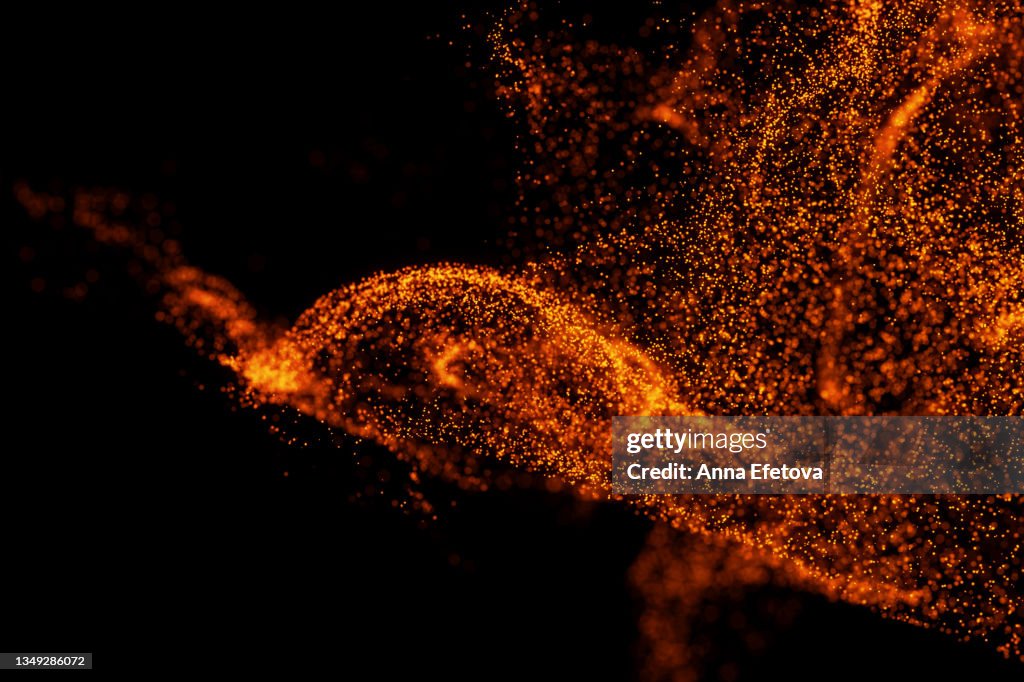 Splash of many little orange particles on black background. Perfect backdrop for your design