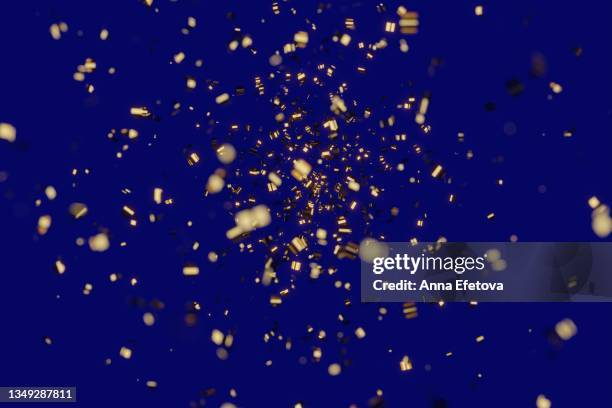 many festive golden confetti on blue background. concept of new year or birthday celebration. perfect backdrop for your design - blue confetti stockfoto's en -beelden