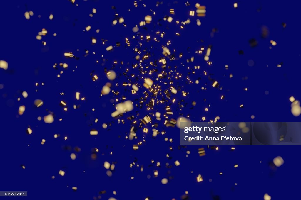 Many festive golden confetti on blue background. Concept of New Year or birthday celebration. Perfect backdrop for your design