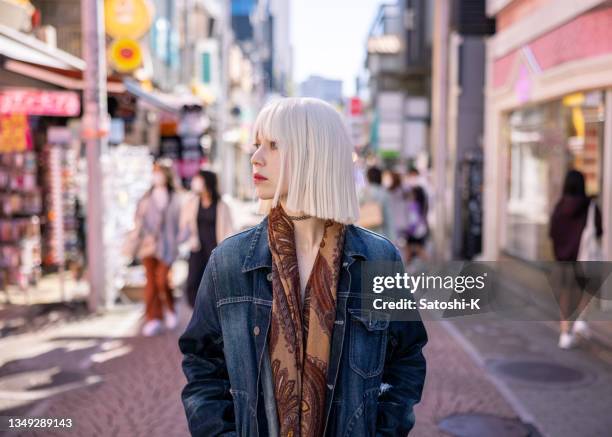 junge frau mit platinblonden haaren beim gang auf der einkaufsstraße - bleached hair stock-fotos und bilder