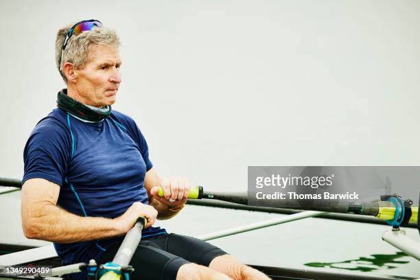 medium wide shot of senior male rower rowing in scull during early morning workout - single scull stockfoto's en -beelden