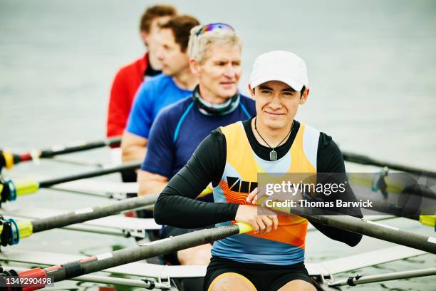 medium shot portrait of smiling male rower sitting in scull with teammates before workout - rowing boat stock pictures, royalty-free photos & images