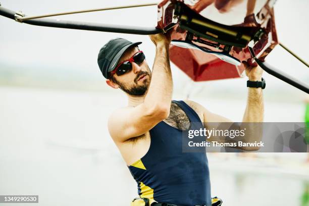 medium shot of male rower lifting scull overhead after early morning workout - single scull stockfoto's en -beelden