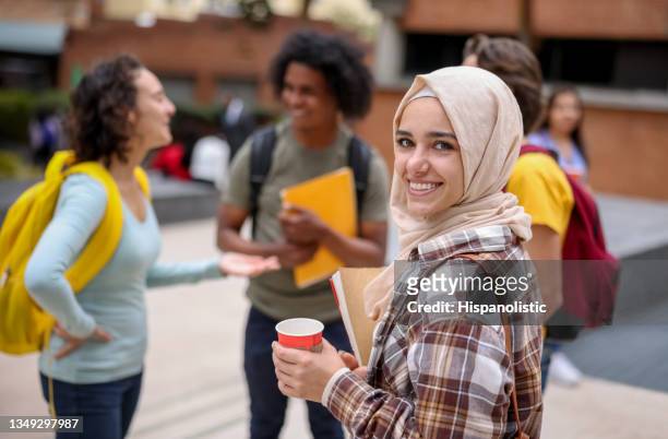 glückliche muslimische studentin, die mit einer gruppe von freunden kaffee trinkt und lächelt - asyl stock-fotos und bilder
