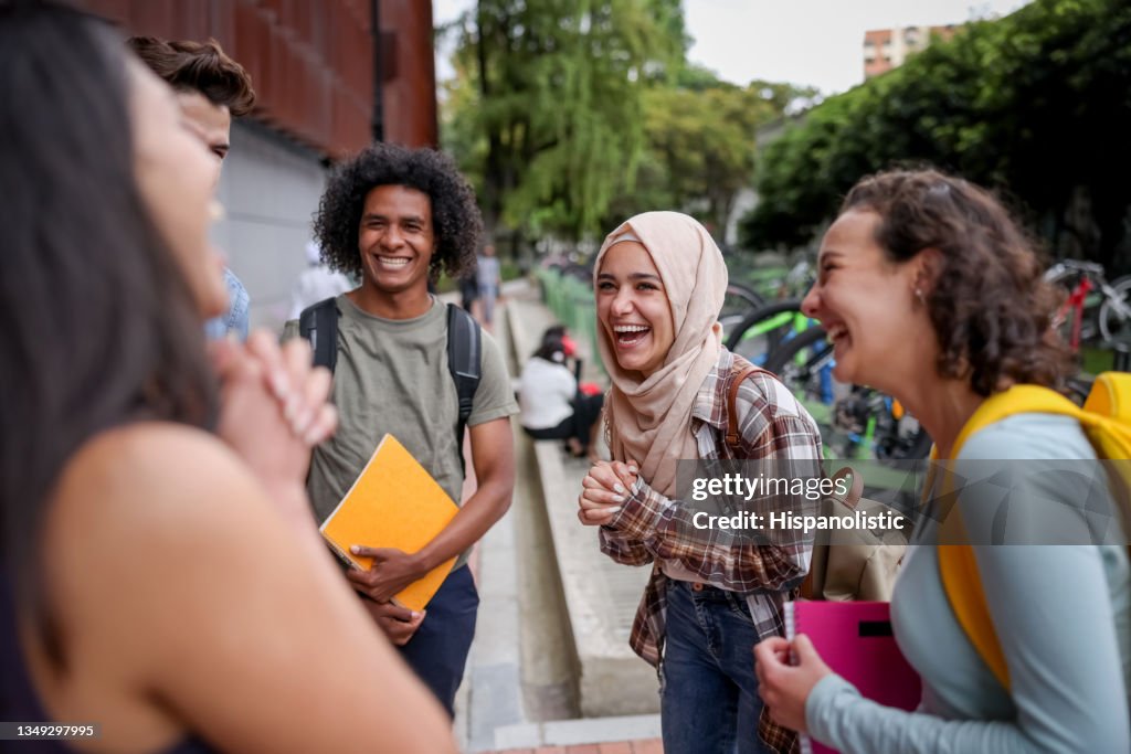 Groupe multiethnique d’élèves qui ont l’air heureux de parler à l’école et de rire