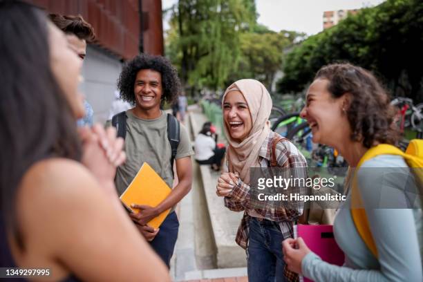 multi-ethnic group of students looking happy talking at the school and laughing - hoofddoek stockfoto's en -beelden