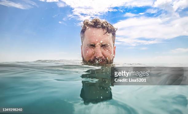 uomo mezzo sott'acqua con solo gli occhi sopra nell'idilliaco oceano blu - half underwater foto e immagini stock