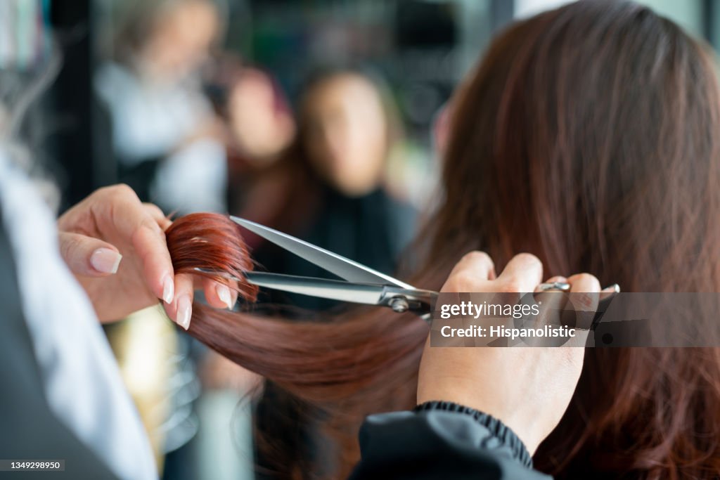 Nahaufnahme eines nicht wiederzuerkennbaren Friseurs, der einer Kundin die Haare schneidet