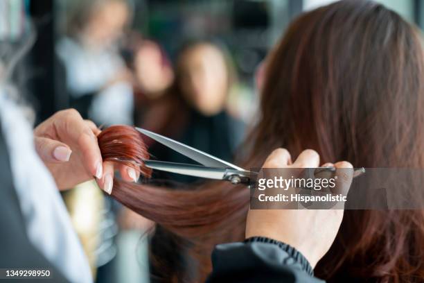 nahaufnahme eines nicht wiederzuerkennbaren friseurs, der einer kundin die haare schneidet - hairstyle stock-fotos und bilder