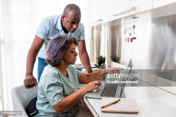 mature couple using laptop at home. - serious couple stock pictures, royalty-free photos & images