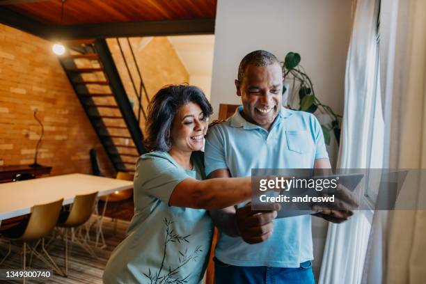 mature couple using digital tablet at home. - 50 59 years stock pictures, royalty-free photos & images
