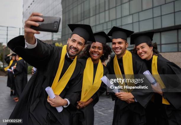 feliz grupo de estudiantes de posgrado tomándose una selfie el día de su graduación - masters degree fotografías e imágenes de stock