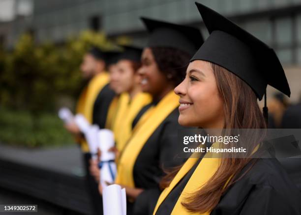 feliz grupo de estudiantes graduados en fila sosteniendo sus diplomas - graduación fotografías e imágenes de stock