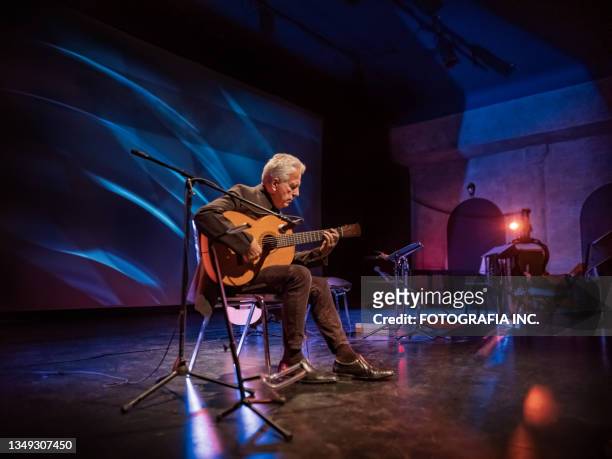mature male guitarist on the stage with classic guitar - world music stockfoto's en -beelden