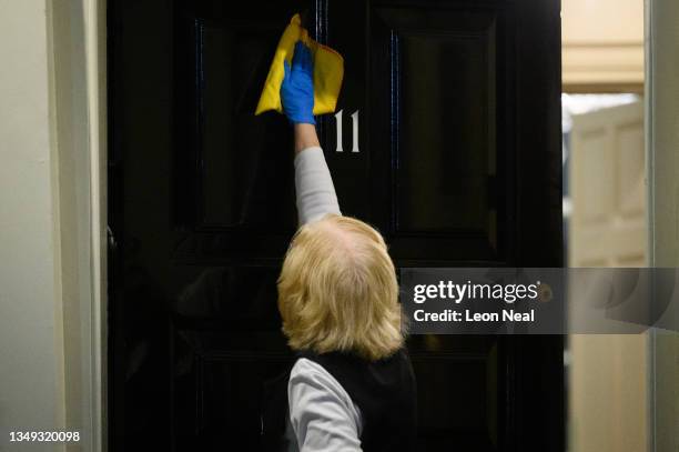 Woman polishes the door of number 11 ahead of the Budget photo call at Downing Street on October 27, 2021 in London, England. In his statement to the...