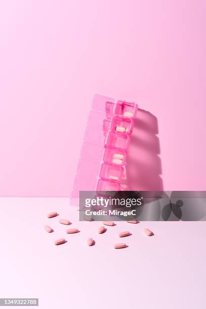 pink pills spilled from the pill organizer - drug addict stock-fotos und bilder