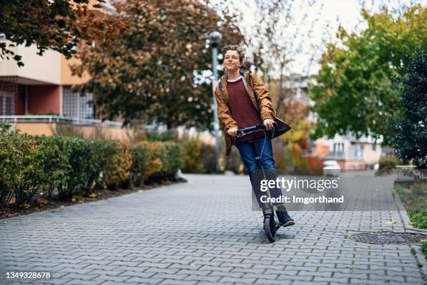 teenage boy riding scooter in the residential area - push scooter stock pictures, royalty-free photos & images