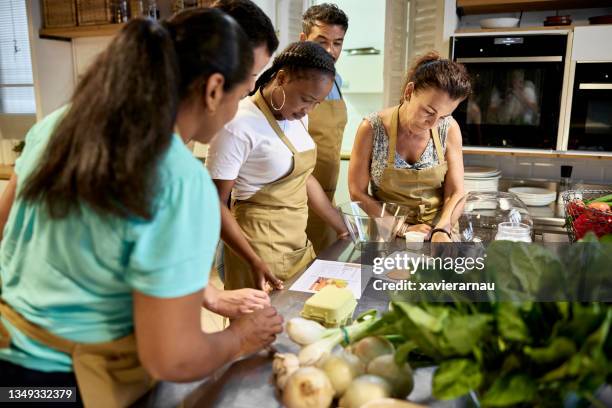 adult students reading recipe in cooking class - teambuilding stockfoto's en -beelden