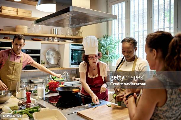 erwachsene schüler, die mit koch im kochkurs arbeiten - cookery class stock-fotos und bilder