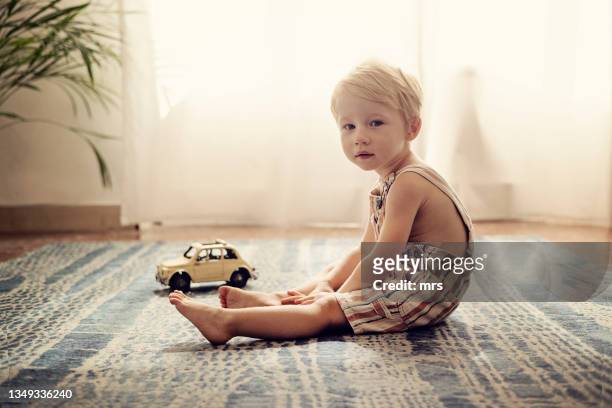 portrait of little boy indoors - sitting on floor fotografías e imágenes de stock