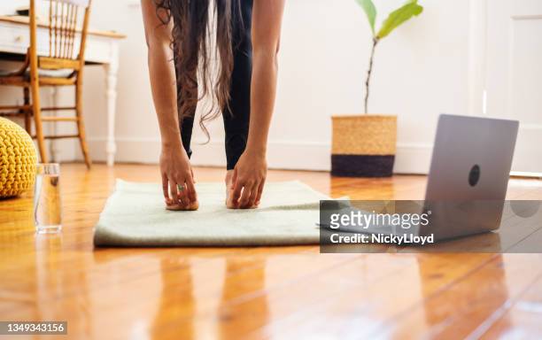 junge frau, die sich während eines online-yoga-kurses dehnt, um ihre zehen zu berühren - zehenspitzen berühren stock-fotos und bilder