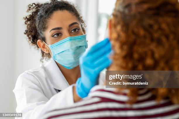 médico que usa mascarilla quirúrgica examinando - visita fotografías e imágenes de stock