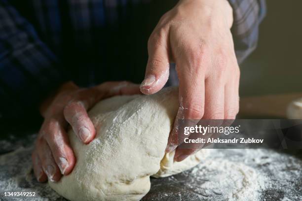 cooking italian vegetarian pizza with vegetables, tomato paste, cheese and mushrooms at home, on a wooden kitchen table. a woman, cook or housekeeper kneads and rolls the dough with her hands. home life. step-by-step instructions, do it yourself. step 1. - kneading stock pictures, royalty-free photos & images