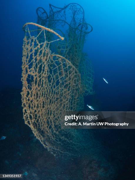 a fishing net abandoned on the seabed - fischnetz stock-fotos und bilder