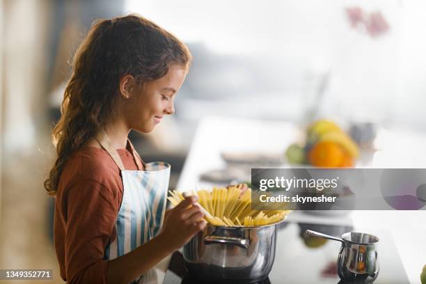 smiling girl cooking spaghetti for lunch. - making dinner stock pictures, royalty-free photos & images